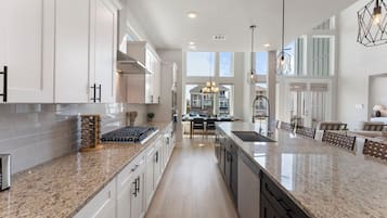 A spacious kitchen with granite countertops, white cabinetry, and a central island.