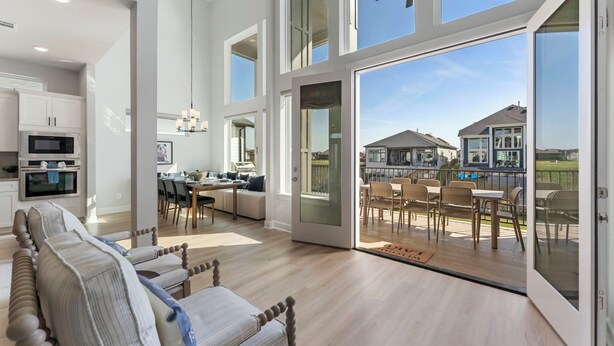A spacious living area with a sofa, dining table, and chairs, a kitchen with modern appliances, and large sliding glass doors leading to an outdoor patio. - Lux Lakefront with Game-room, Community Pool, Paddleboards, and more! (Willis)