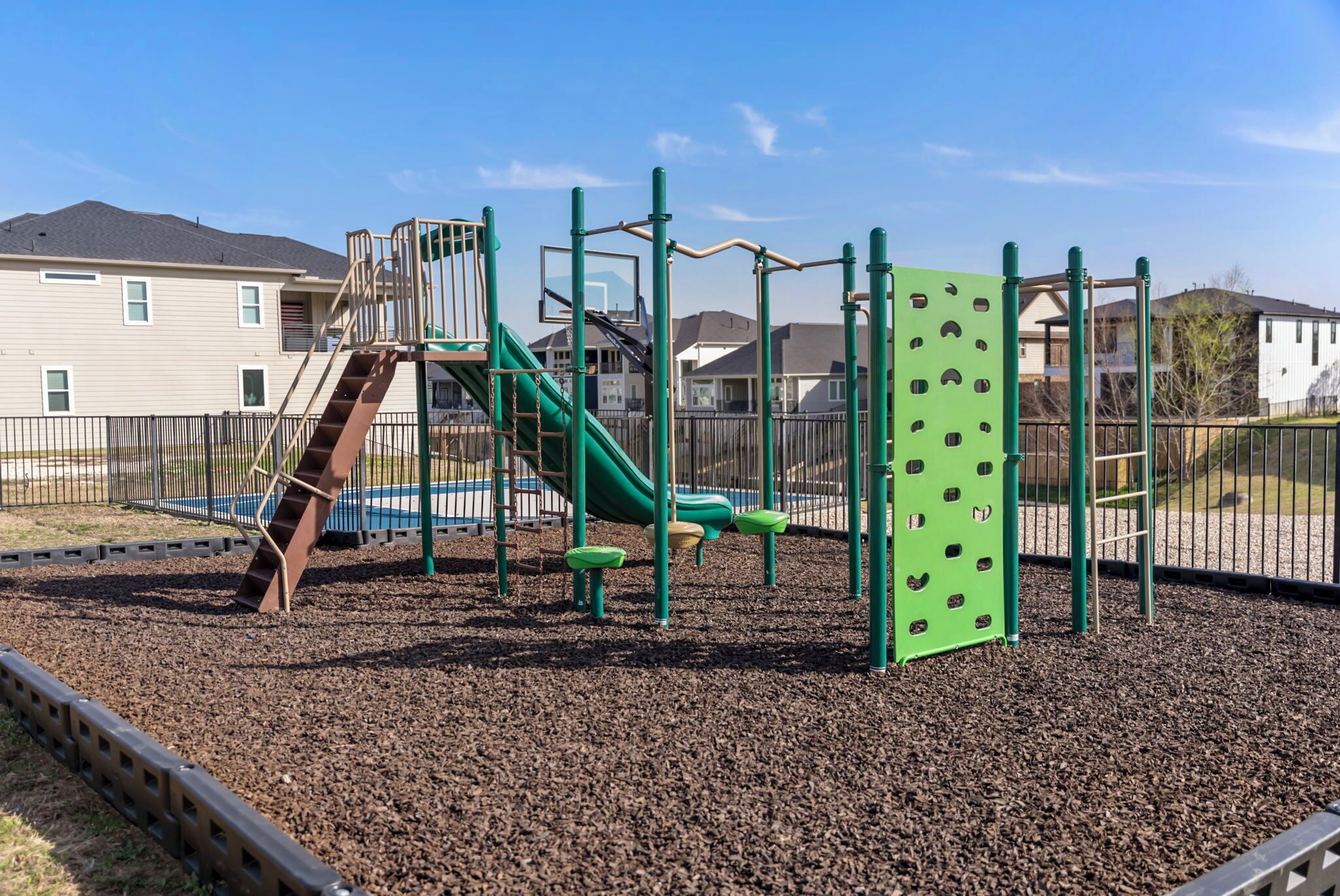 Ein Spielplatz mit Rutsche, Klettergerüsten und einer grünen Kletterwand.