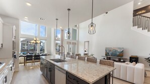 A spacious kitchen with a large island, modern pendant lights, and a view to the outside. - Lux Lakefront with Game-room, Community Pool, Paddleboards, and more! (Willis)