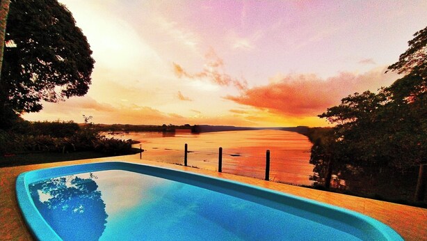 A swimming pool with a view of a sunset over a body of water. - Casa de Temporada Felicidade, 38 Hóspedes, 2 Piscinas, 9 Suítes e 2 Churrasqueiras em Itacaré Bahia  (Itacaré)
