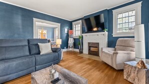Una sala de estar con una pared azul, una chimenea, un televisor y un sofá.