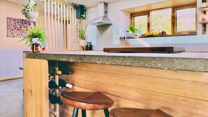 A modern kitchen with wooden bar stools, a built-in wine rack, and potted plants.