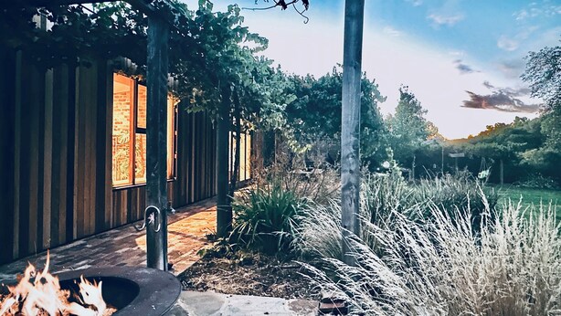 A stone pathway leading to a wooden building with a fire pit.
