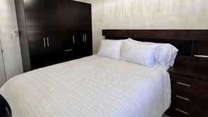 Une chambre à coucher avec un grand lit, une armoire en bois foncé et un lustre.