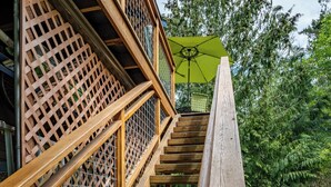 A wooden staircase with a green umbrella at the top, surrounded by lush greenery. - Tranquil, private Whidbey Island apt.  Level 2 charging station, pet friendly. (Freeland)