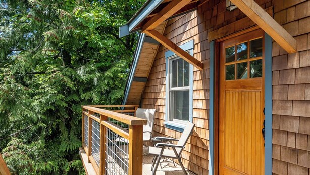 A wooden cabin with a balcony, a door, and a window. - Tranquil, private Whidbey Island apt.  Level 2 charging station, pet friendly. (Freeland)