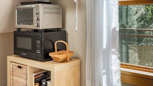 A kitchenette with a toaster oven, a microwave, and a basket on a wooden stand. - Tranquil, private Whidbey Island apt.  Level 2 charging station, pet friendly. (Freeland)
