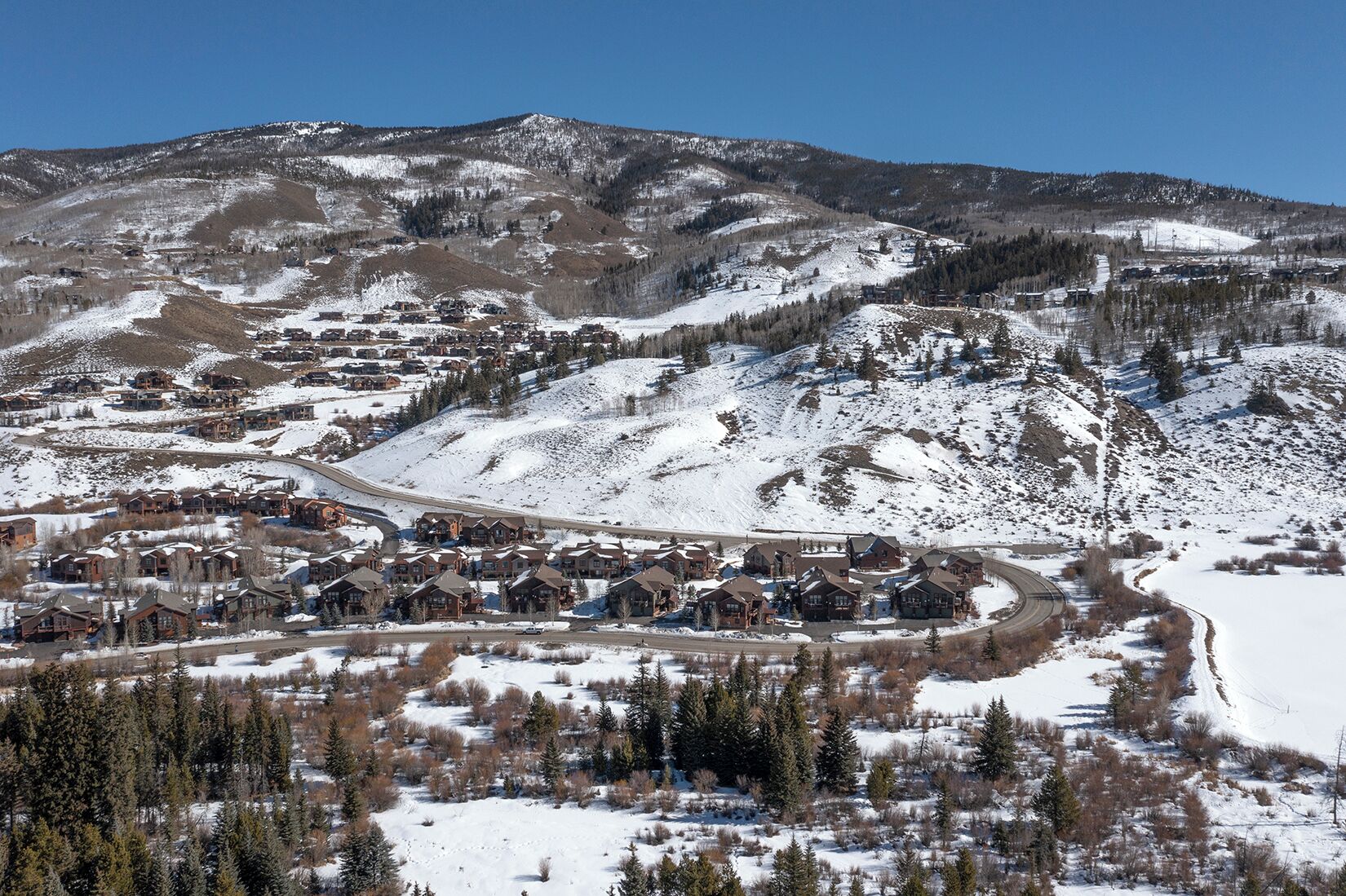 Une ville de montagne enneigée, avec une route sinueuse et des maisons aux façades en bois.