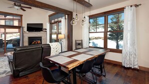 Un comedor con una mesa de madera, sillas negras, una chimenea y un televisor.