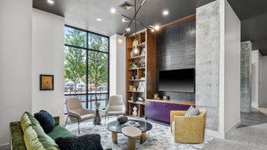 Un salon moderne avec un canapé vert, une table basse ronde et une bibliothèque.