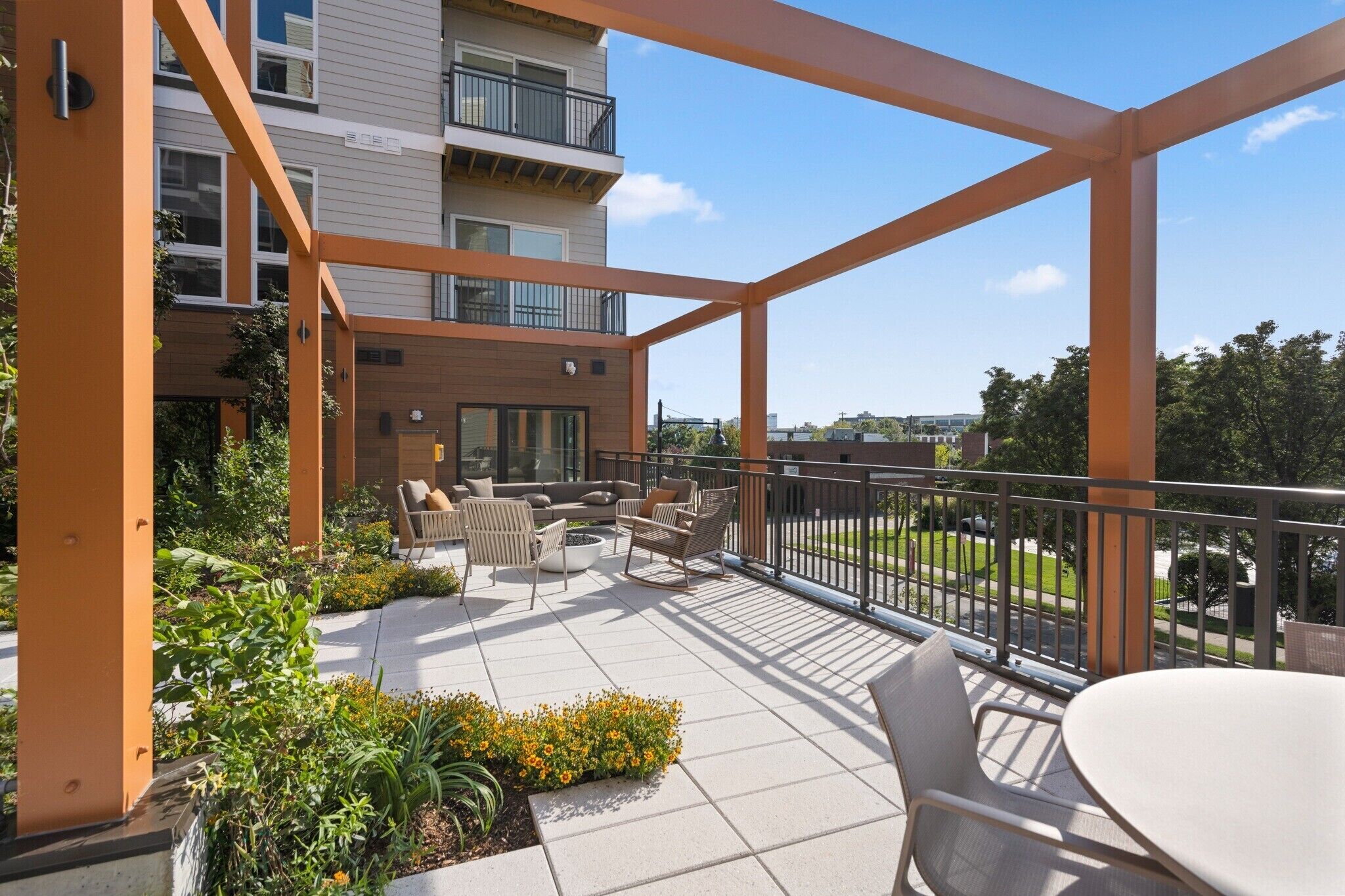 A covered outdoor patio with seating and a view of a building.