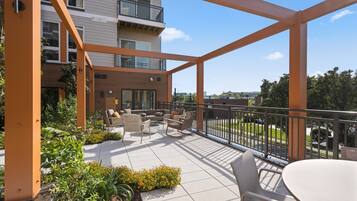 A covered outdoor patio with seating and a view of a building.