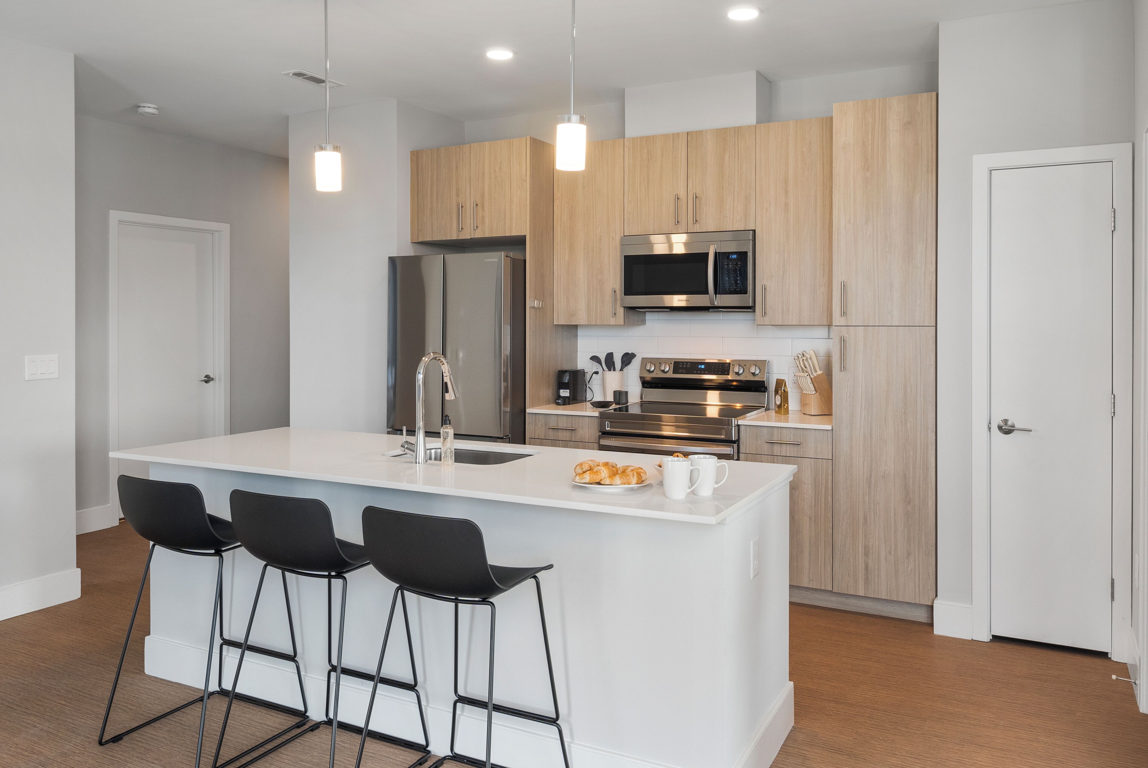 A modern kitchen with a central island, stainless steel appliances, and wooden cabinetry.