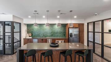 Una cocina moderna con una isla central, luces colgantes y un salpicadero verde.