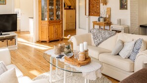 A living room with a sofa, a glass coffee table, a wooden cabinet, and a television.