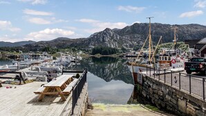 A marina with boats docked, a wooden pier, and a mountain in the background.