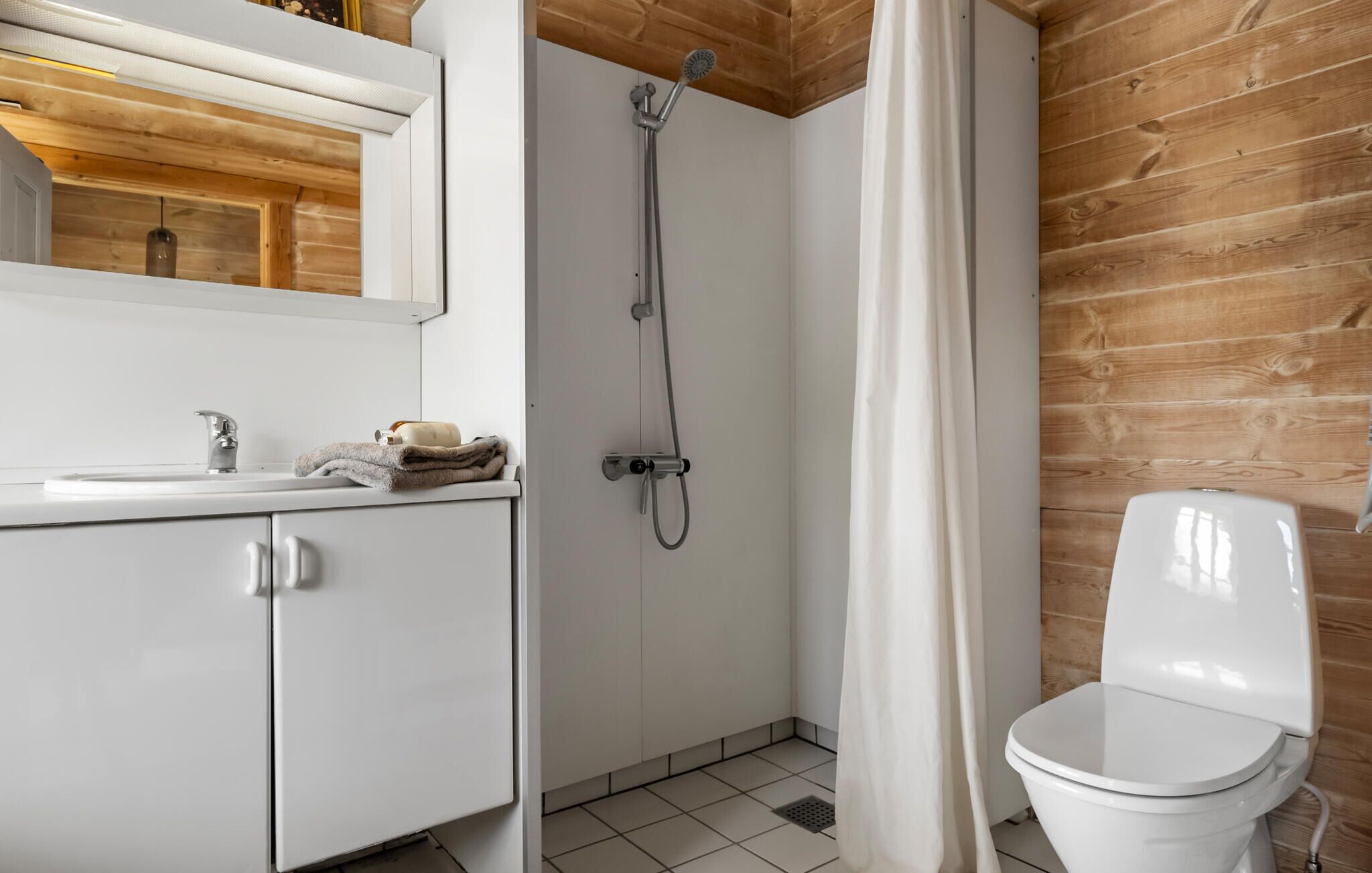Une salle de bain avec douche, toilettes et lavabo.