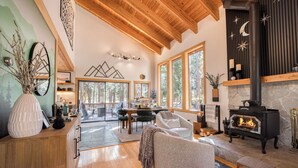Una sala de estar acogedora con chimenea, vigas de madera y ventanas amplias.