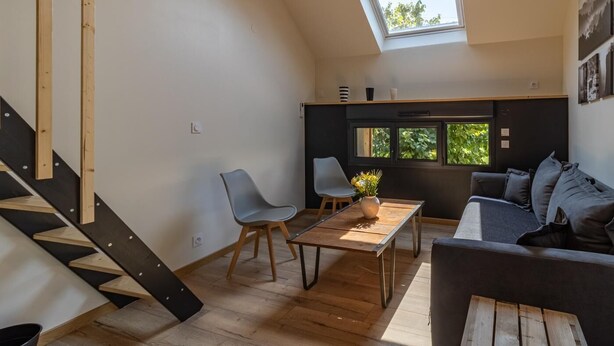 A modern interior with a staircase, a dining area, and a seating area with a sofa and chairs.