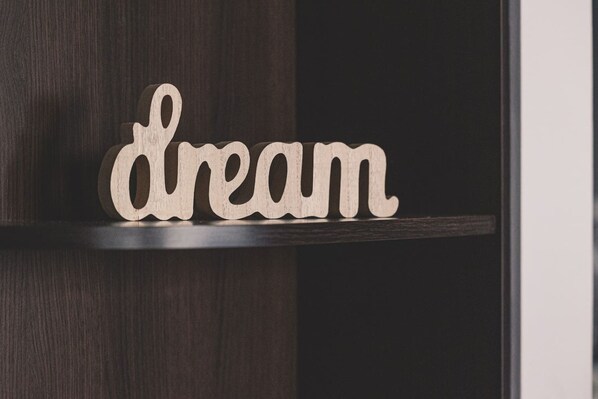Un letrero de madera con la palabra 'dream' sobre una estantería de madera oscura.