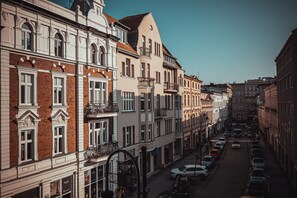 Vista de una calle con una hilera de edificios históricos de fachadas uniformes, adoquinada y con coches estacionados.