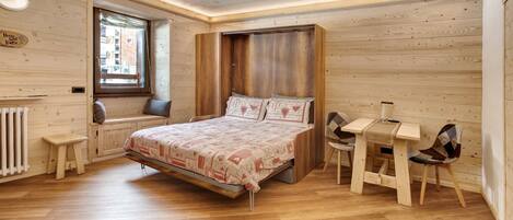 Una habitación con paneles de madera, una cama, una mesita y una silla.