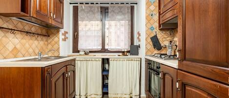 Een koelkast, een oven, een kookplaat, kookgerei, borden en bestek