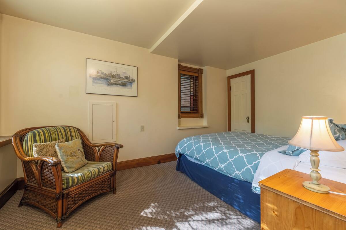 Une chambre à coucher avec un lit, une chaise, une lampe, une fenêtre et une porte.