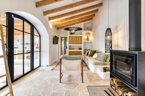 A cozy living room with a stone floor, a fireplace, a sofa, and a dining area with wooden cabinets. - Villa 'Las Brisas' with Mountain View, Wi-Fi and Air Conditioning (Jávea)