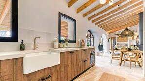 Een moderne keuken met houten kastjes, een wit aanrechtblad en een grote spiegel.