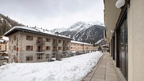 A snow-covered pathway leading to a building with stone walls and a balcony.