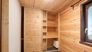 A wooden interior with a sliding door closet, a window with a heart design, and a tiled floor.