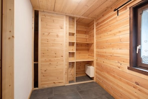 Ein Holzinnenraum mit Schiebetürenschrank, einem Fenster mit Herzmotiv und Fliesenboden.