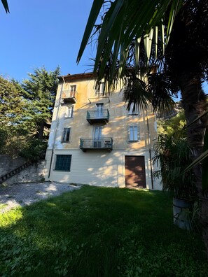 A multi-story building with balconies, a garage, and a grassy area.
