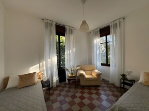 A room with a checkered floor, two beds, a sofa, a chair, and a table with a vase. - Apartment 'Francesco' 1of4 of Villa Paruzzi 6 Min To Lake Como (Dervio)