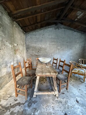 A rustic wooden dining table with six chairs, a large white bowl, and scattered leaves on the floor. - Apartment 'Francesco' 1of4 of Villa Paruzzi 6 Min To Lake Como (Dervio)