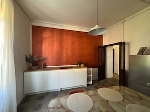 A modern kitchen with white cabinetry, a marble countertop, and a pendant light.