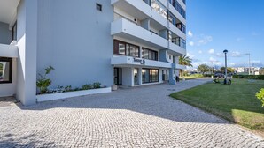 Un hotel de varios pisos con entrada pavimentada, zona de estar al aire libre y un letrero que indica un restaurante.