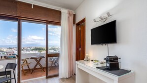 Habitación moderna con un ventanal grande, televisor de pantalla plana, cafetera y comedor con mesa y sillas.