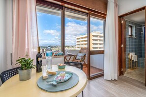 Un balcon avec une table dressée pour le dîner, une plante en pot et une bouteille de vin.
