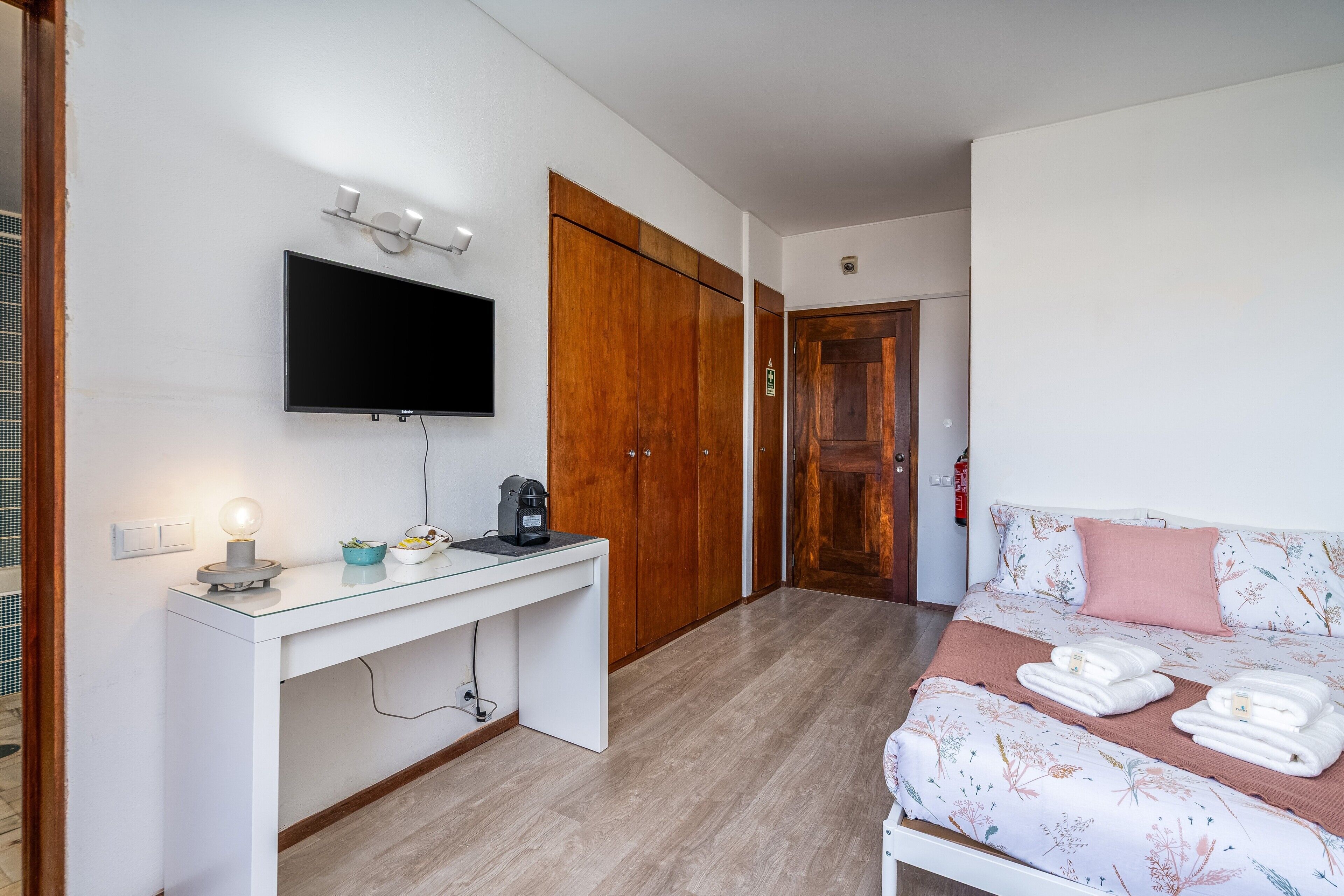 Habitació d'hotel amb llit, escriptori amb televisió de pantalla plana, cafetera i armari.