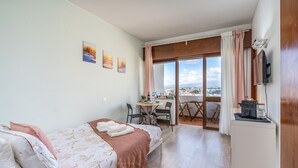Un dormitorio con cama, escritorio, silla y vistas de la ciudad.