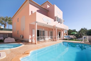 A two-story building with a swimming pool, outdoor seating, and a covered patio area.