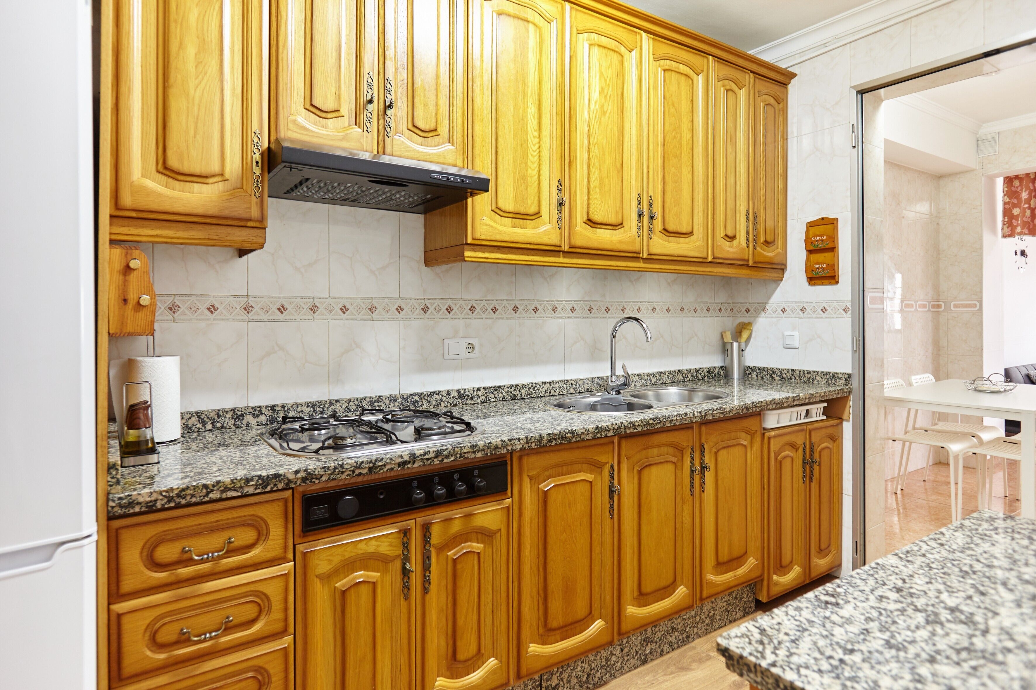 Una cucina con mobili in legno, un piano di lavoro in granito, un fornello e una lavastoviglie.