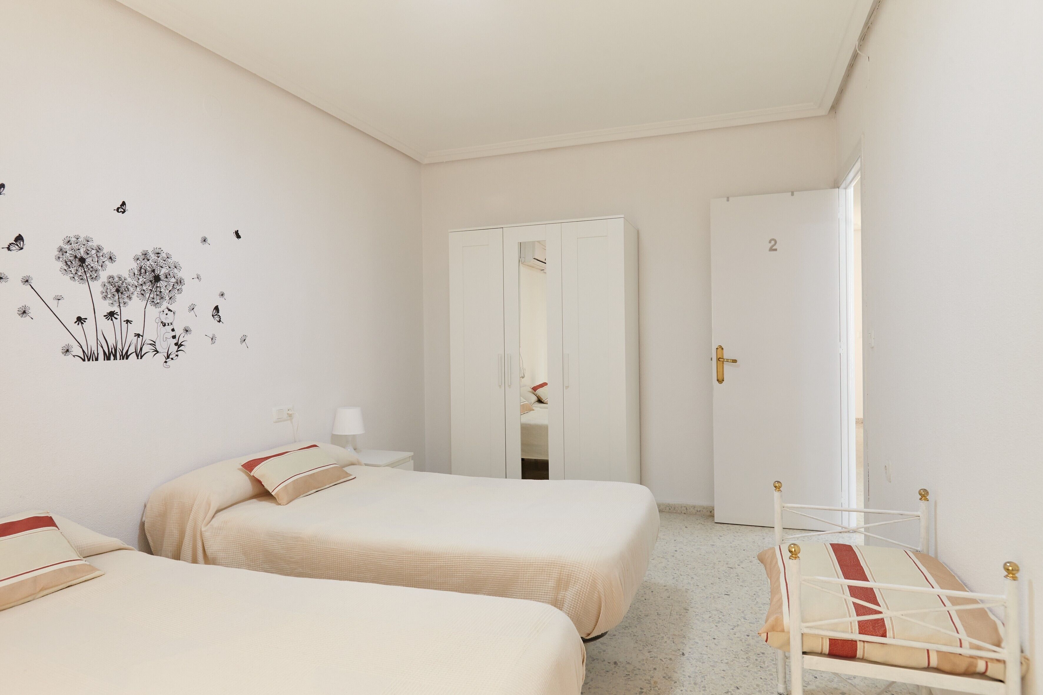 Une chambre avec deux lits, une chaise, une armoire et un miroir.