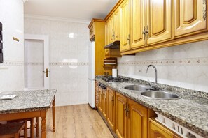 Eine Küche mit Holzschränken, einer Granit-Arbeitsplatte, einer Edelstahl-Spüle und einem eingebauten Backofen.