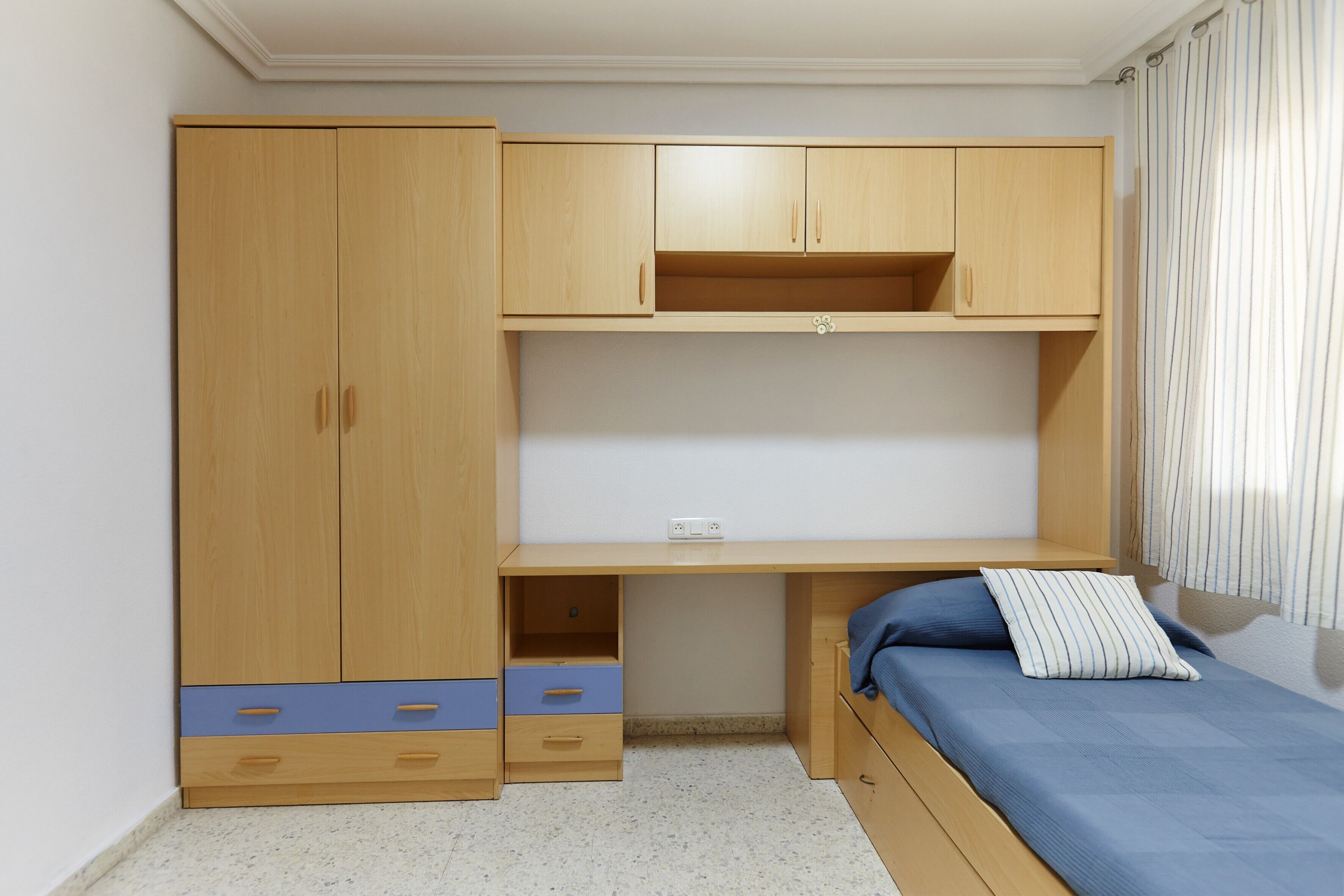 Un dormitorio con un armario de madera, un escritorio y una cama.