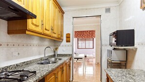 A kitchen with granite countertops, wooden cabinets, a gas stove, and a microwave.