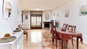 A dining area with a checkered floor, a dining table with chairs, a TV, and a fireplace.